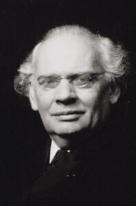 ピアニストで作曲家のユリウス・レントゲンのポートレート。胸から上を写した写真。白髪で、メガネをかけている。微笑んでカメラをまっすぐ見ている。