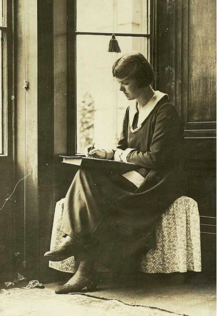 何かに腰掛け膝の上に置いた本の表紙の上で楽譜を書くハウエル